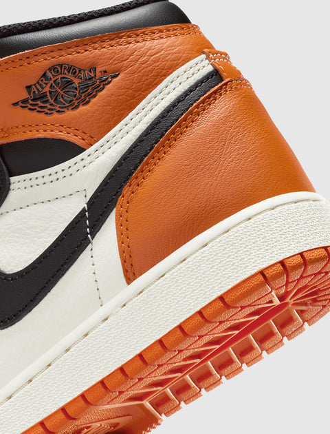 Close-up of Air Jordan 1 sneaker in orange, white, and black leather with embossed logo