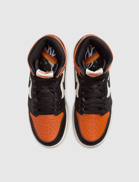 Top view of high-top sneakers with orange, black, and white leather panels and black laces