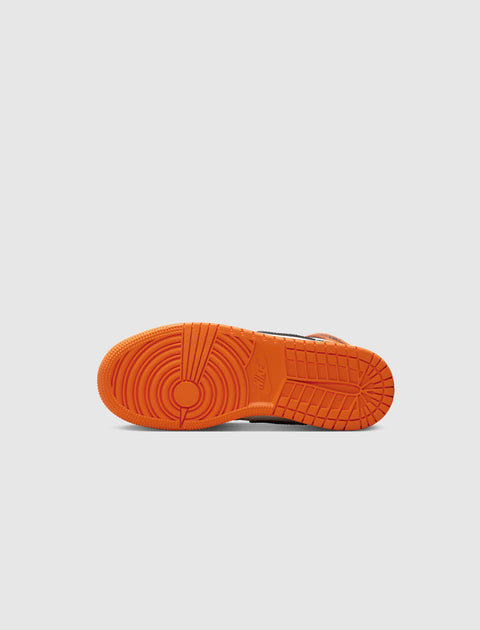 Orange rubber outsole of a sneaker against a plain light background