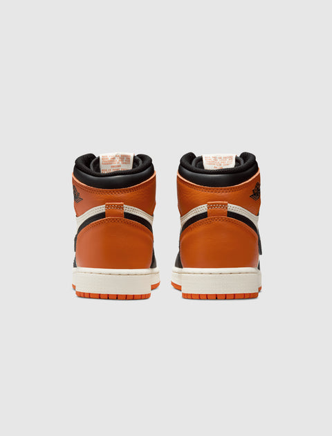 Rear view of orange, black, and white high-top sneakers on a light background.