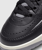 Close-up of black leather sneaker toe with perforated details, black laces, and white sole