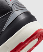 Close-up of sneaker heel with black, grey, red, and white color details and textured sole