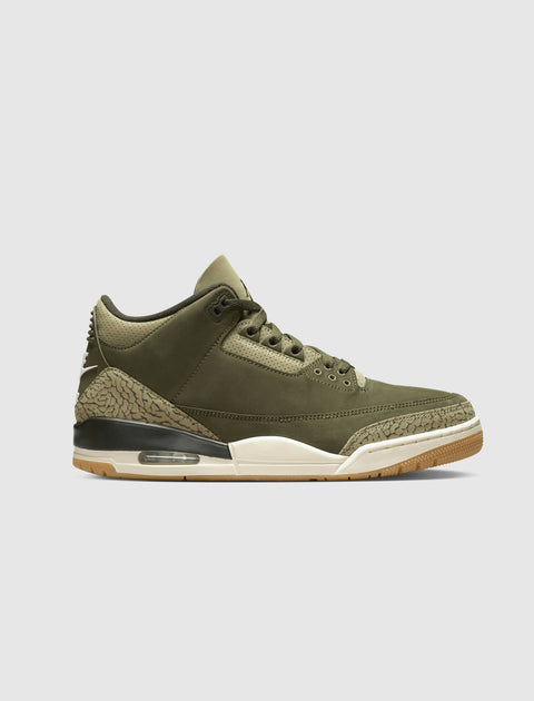 Olive green sneaker with crackle print accents, air sole, and white midsole on gray background.