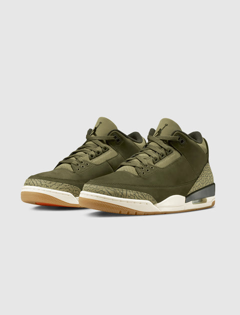 Olive green sneakers with textured midsole, gum outsole, and visible air unit on white background