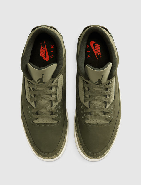 Olive green Nike Air sneakers with red branding and textured midsoles, top view