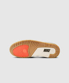 Shoe outsole with gum, white, and red accents, displaying the Nike logo on the sole.