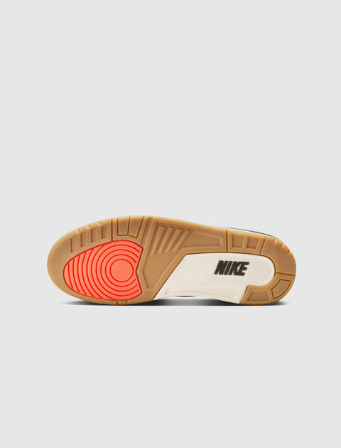 Shoe outsole with gum, white, and red accents, displaying the Nike logo on the sole.
