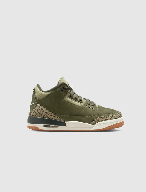 Olive green sneaker with suede upper, camouflage accents, and gum sole on white background