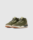 Olive green sneakers with textured beige accents and gum soles on a light background