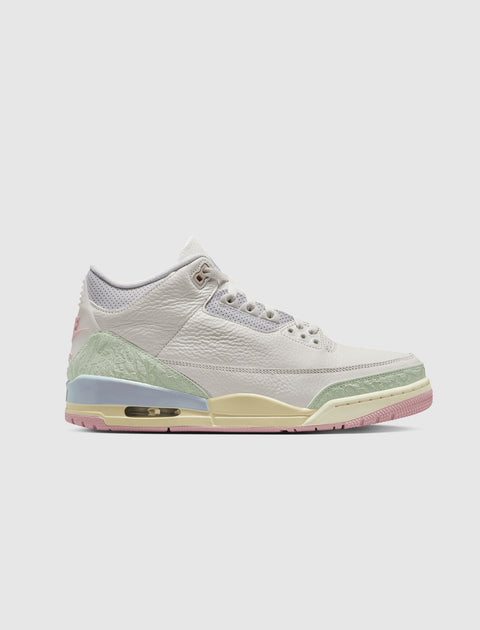 White leather sneaker with pastel green, yellow, and pink accents on a light background