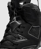 Close-up of black high-top sneaker with perforated panels and embroidered basketball logo