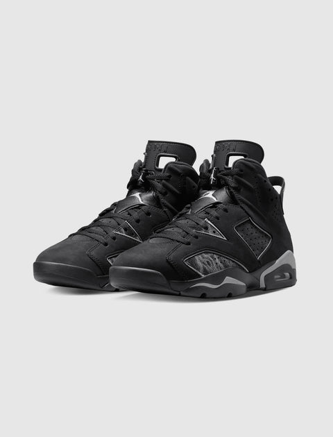 Pair of black high-top sneakers with suede panels and visible air cushioning on a gray background