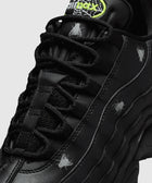 Close-up of black sneaker with silver fly graphics and neon green Air Max logo on tongue