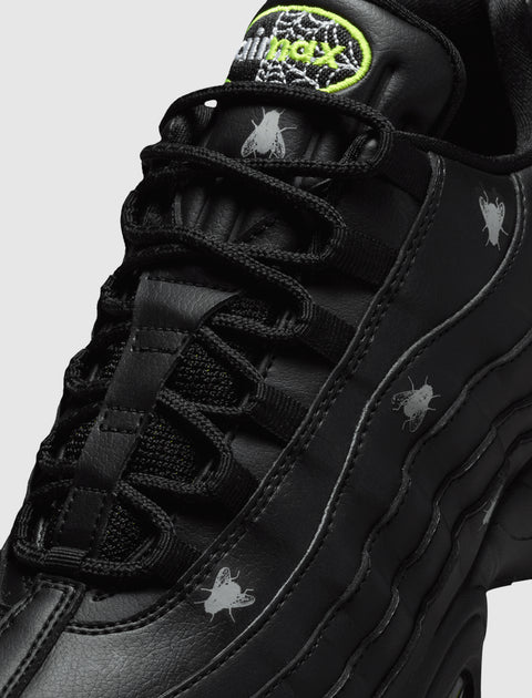 Close-up of black sneaker with silver fly graphics and neon green Air Max logo on tongue