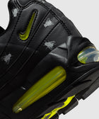 Closeup of black sneaker with yellow accents and fly graphics on leather upper