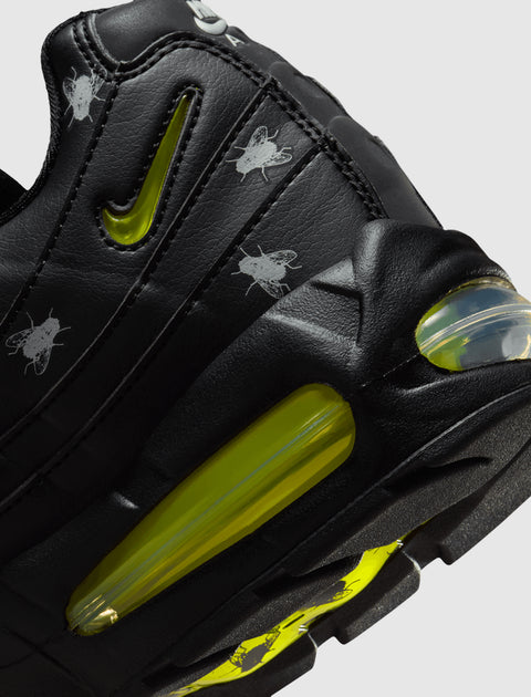 Closeup of black sneaker with yellow accents and fly graphics on leather upper