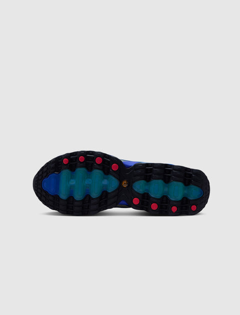 Blue sneaker outsole with black tread, teal accents, and red grip details on white background