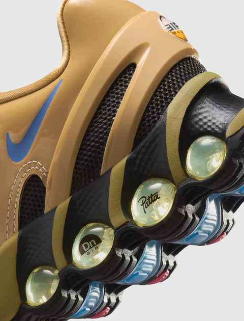 Close-up of tan sneaker with blue swoosh, black mesh, visible air cushioning and Patta logo