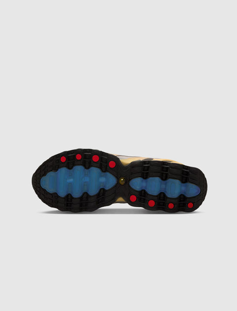 Close-up of sneaker outsole with black, blue, and red tread pattern on light background