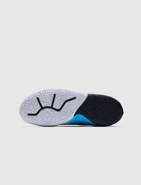 Closeup of sneaker sole with textured black and white pattern and blue accent on a gray background