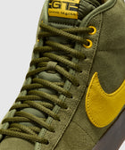 Olive green suede mid-top sneaker with yellow Swoosh and yellow label details