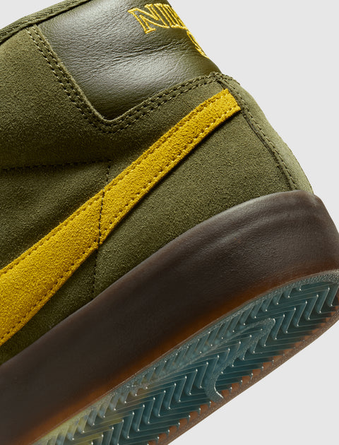 Close-up of olive green suede sneaker with yellow stripe and textured sole