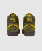 Olive green and yellow suede mid-top skate shoes, rear view, with bold embroidered logos
