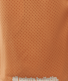 Close-up of orange mesh athletic shorts with 'all points bulletin.' text near the hem.
