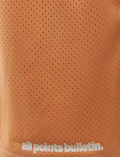 Close-up of orange mesh athletic shorts with 'all points bulletin.' text near the hem.