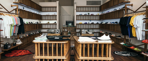 Modern streetwear boutique with men's sneakers, colorful t-shirts, and wooden display shelves