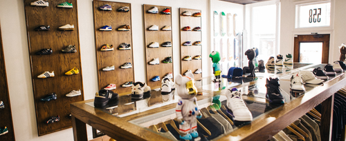 Sneaker store interior with streetwear sneakers on display walls and glass counter, hanging apparel