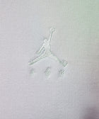 Close-up of white embroidered basketball logo on light fabric streetwear apparel