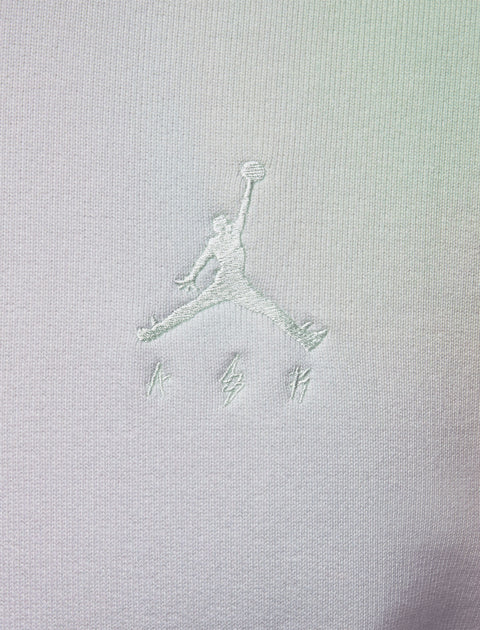 Close-up of white embroidered basketball logo on light fabric streetwear apparel