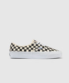 Low-top sneaker with black and white checkerboard pattern and white sole on neutral background