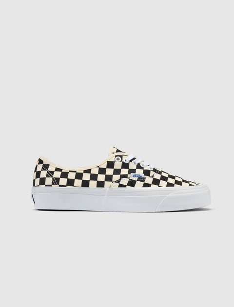 Low-top sneaker with black and white checkerboard pattern and white sole on neutral background