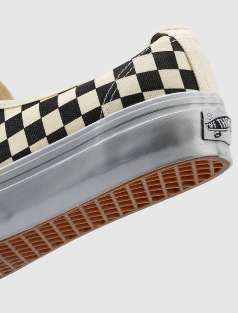 Close-up of black and white checkerboard canvas sneaker with gum sole and rubber trim
