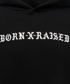 Black hoodie with white gothic 'Born X Raised' text on chest, men's streetwear apparel.