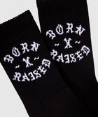 Black ribbed crew socks with white Born x Raised text, streetwear apparel closeup