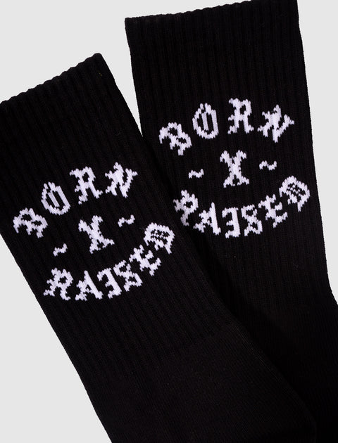 Black ribbed crew socks with white Born x Raised text, streetwear apparel closeup