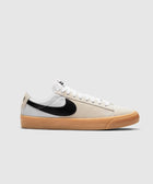 White and beige low-top sneaker with black swoosh logo and gum rubber sole on a plain background