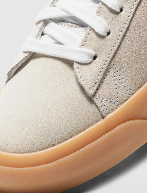 Close-up of beige suede sneaker with white laces and gum rubber outsole