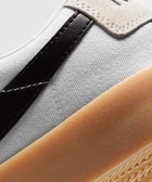 Closeup of white canvas sneaker with black leather detail and gum rubber sole