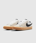 Low-top white and beige sneakers with black swoosh and gum sole on plain background