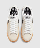 White and beige low-top sneakers with black swoosh and gum sole, viewed from above