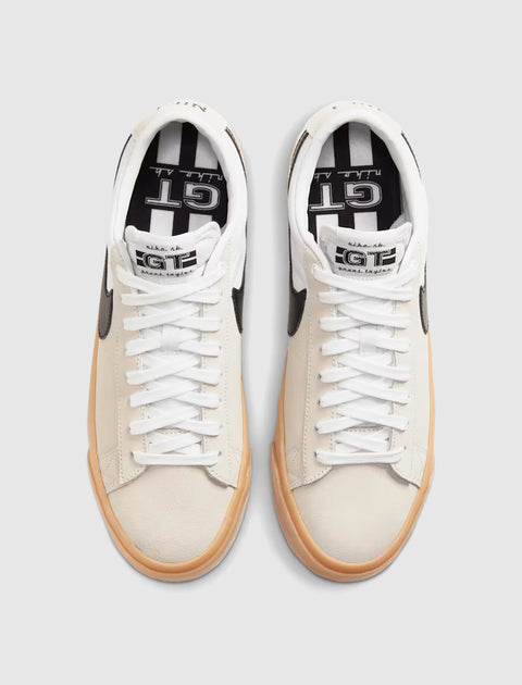 White and beige low-top sneakers with black swoosh and gum sole, viewed from above