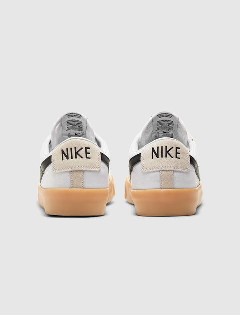 White low-top sneakers with black accents and gum soles, viewed from the back.