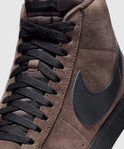 Close-up of brown suede high-top sneaker with black swoosh and black laces