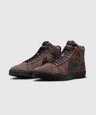 Brown suede high-top sneakers with black Swoosh logo and black soles, side by side on gray background