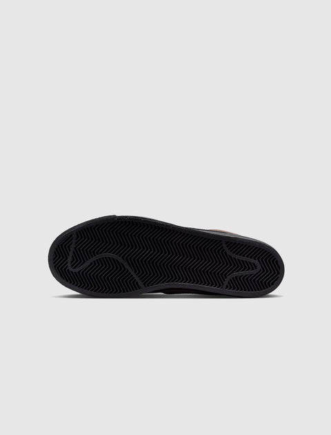 Black sneaker sole with herringbone tread pattern on a light gray background