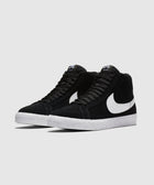 Black and white high-top sneakers with white swoosh and textured white sole on gray background